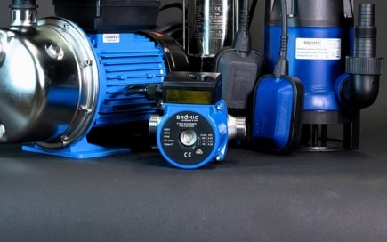 A collection of blue and metallic water pumps is displayed on a dark surface. One prominently features text: 