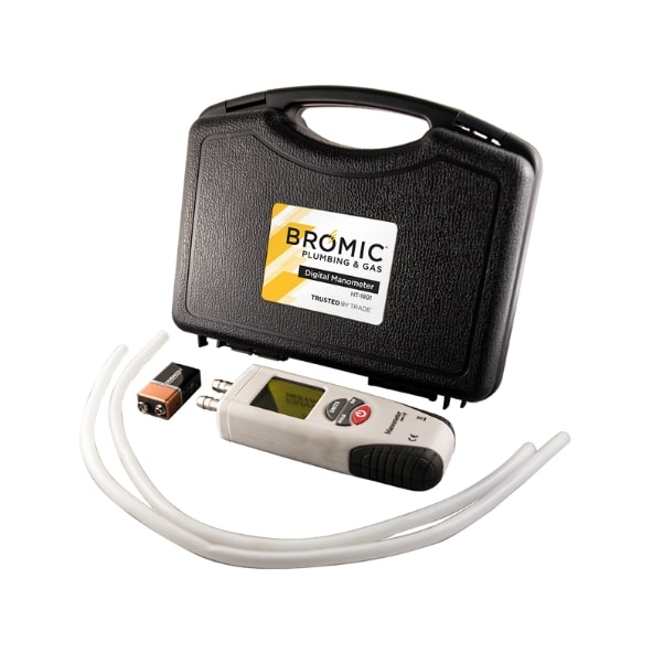 A digital manometer with tubes and a battery lies next to a black carrying case labeled 