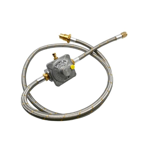 A metal gas regulator with attached flexible hoses lies coiled. The central regulator reads 