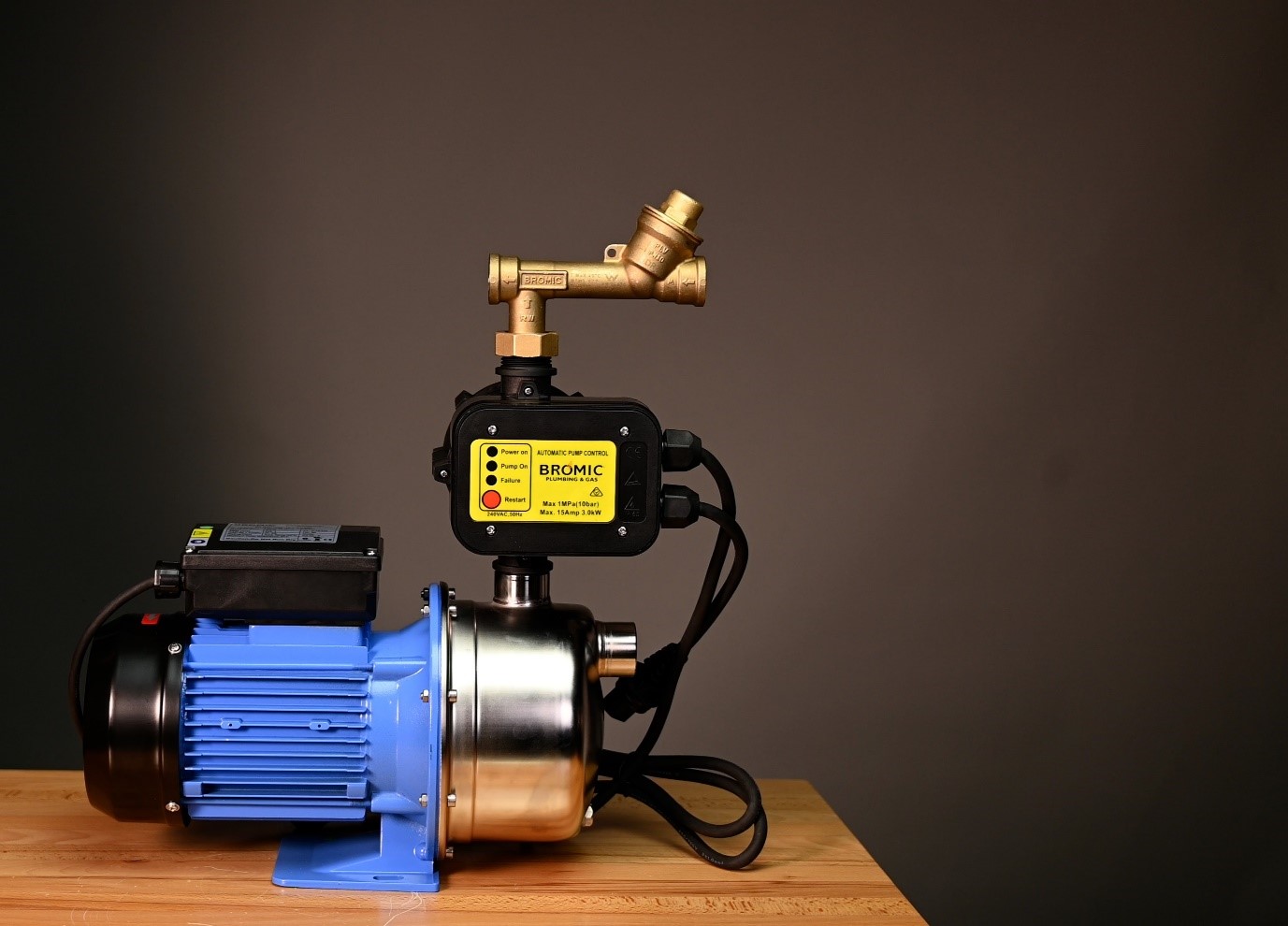 Pump resting on a wooden surface, featuring blue and metallic components, equipped with a brass valve and labeled 